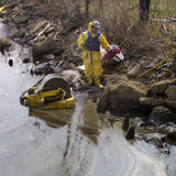 worker cleaning up oil spill in water